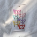 Lot de six barrettes papillon colorées aux tons macarons sur un fond en tissu blanc doux - Style Papillon