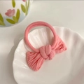 Pink fabric bow hair tie with ribbed texture on a white decorative shell plate - Pink