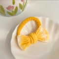 Cute yellow knit bow hair tie for girls featuring soft ribbed texture on a white shell plate - Gradient Yellow