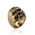 Macro shot of silver skull ring with gold engravings and black stone inset eyes - US 10 / Gold