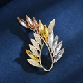 Elegante olijftak broche met oranje kristalverloop op een gouden metalen frame - Goud