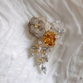 Detailed macro view of camellia brooch with orange gemstone and crystal petals - Yellow Zirconia