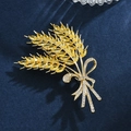 Vue macro d'une broche d'épi de blé doré avec zircons ambrés et perles sur velours - Forme de Blé à 3 Épis