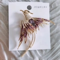 Macro detail of phoenix brooch with purple enamel wings and sparkling crystal inlay - Purple