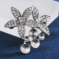 Detailed macro view of silver flower brooch base with rhinestone petals and pearl settings - Grape Beaded Style