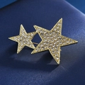 Détail macro de broches en forme d'étoiles dorées entrelacées avec strass en cristal brillant - Étoile à cinq branches