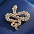 Macro detail of a golden snake brooch with sparkling white crystals on blue silk - Gold Rhinestone Snake Shape / Gold Snake