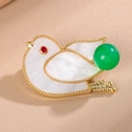 Detailed close-up of bird brooch with white shell inlay, gold trim, and green bead accent - Green