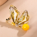 Elegante spilla a farfalla dorata con ali ambrate traslucide e ciondolo a nappa lucida - Giallo Limone