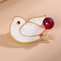 Macro shot of bird brooch with white shell inlay, red rhinestone eye and a berry bead - Red