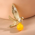 Elegant gold bird brooch with amber-like pearl bead and intricate wing textures - Gold