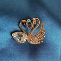 Elegante gouden dubbele zwaan broche met kristallen en peervormige edelsteen op blauwe stof - Goud