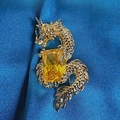 Detailed close-up of a golden dragon brooch featuring a large yellow zircon stone center - Golden Dragon Coiled Around Bead