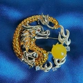 Detailed view of dragon brooch with micro-set zircon and yellow resin bead on blue silk - Dragon Gazing At Bead