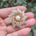 Eleganter goldener Broschen-Sonnenstrahl mit weißer Perle und schimmernden Zirkonia-Akzenten - Goldenes Windrad
