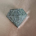 Dettaglio di una spilla argentata a forma di diamante con strass lucidi su seta - Stile Diamante Argento / Bianco