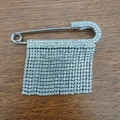 Spilla a balia argentata con nappe di strass brillanti su superficie in legno - Stile Spilla in Strass Diritta Argento