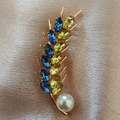 Dettaglio macro della spilla spiga con cristalli blu e perla su seta rosa - Oro Blu Giallo