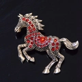 Vista macro della spilla a forma di cavallo vintage in oro con strass rossi brillanti - Rosso