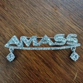Makroaufnahme der silbernen AMASS Buchstaben Brosche mit Strass und Kristallanhängern - Silber