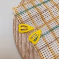 Detail view of two mini yellow heart-shaped metal hair clips on a wooden tray - Bright Yellow
