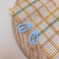 Close-up of light blue heart-shaped matte hair clips on a yellow lace background - Light Blue