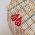 Close-up of red heart-shaped painted mini BB hair clips on checkered fabric background - Red