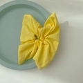 Bright yellow fabric scrunchie with cute bow-like folds on a mint decorative tray - Bright yellow