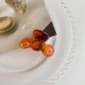 Vista detallada de una pinza para el cabello ámbar translúcida en un plato decorativo - Marrón Transparente