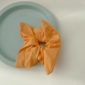 Vibrant orange fabric scrunchie with soft linen texture on a decorative tray - Light Orange