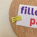 Sparkly yellow bone-shaped snap hair clip with glitter finish on a wooden base - Light Yellow