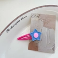 Pinza para el pelo con forma de estrella rosa y azul en colores pastel sobre un plato - Estrella azul