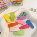Macro shot of colorful candy-colored metal hair clips in a white cloud ceramic dish - Waterdrop Style