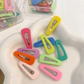 Primer plano de pinzas para el cabello de colores en una bandeja decorativa de cerámica - Estilo de Gota de Agua Hueca