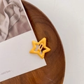Star-shaped hair clip in vibrant yellow enamel finish on a wooden display tray - Drip Glue Orange