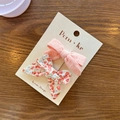 Set aus rosa Stoffschleifen-Haarclips und roten Blumenmustern auf einer Karte - Einfache Schleife Und Blumen Schleife Stil