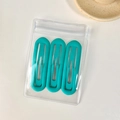 Three matte turquoise hair clips in a clear retail bag on a minimalist background - Oval Peacock Blue