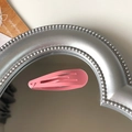 Matte pink teardrop snap hair clip for girls on a reflective silver mirror surface - Bright Pink