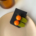 Set of two orange fruit-shaped hair clips on display card with a green velvet base - Orange