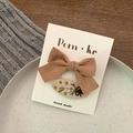 Brown fabric bow and white daisy embroidered oval hair clip set on a display card - Bow And Oval Floral Style