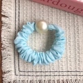 Elegante elastico azzurro con grande perla sintetica su un tappetino intrecciato - Celeste
