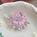 Elastico per capelli a spirale rosa iridescente con perle colorate su piatto - Rosa
