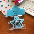 Star-shaped 6cm hair clip in light blue glitter finish on a decorative wooden background - Blue