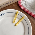 Pair of yellow hollow star-shaped matte metal hair clips for girls on a white ceramic plate - [3] A Pair Of Egg Yolk Stars