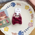 Set of two wine red bow fabric hair ties with high elasticity in a lifestyle setting - Burgundy