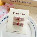 Set of two rose gold sequin bow hair clips with red velvet centers on display card - Brown Series