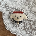 Broche chiot en tissu fait main avec béret rouge et clochette dorée sur fond en bois - Pince Chien