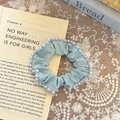 Light blue fabric scrunchie with faux pearls on a vintage book background - Blue
