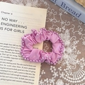 Elegant purple scrunchie with faux pearl edges on an open book for a soft aesthetic look - Purple