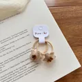 Detail van twee handgebreide bloemen haarelastiekjes in beige met bruine bloemcentra - Beige Ster Haarelastiekje
